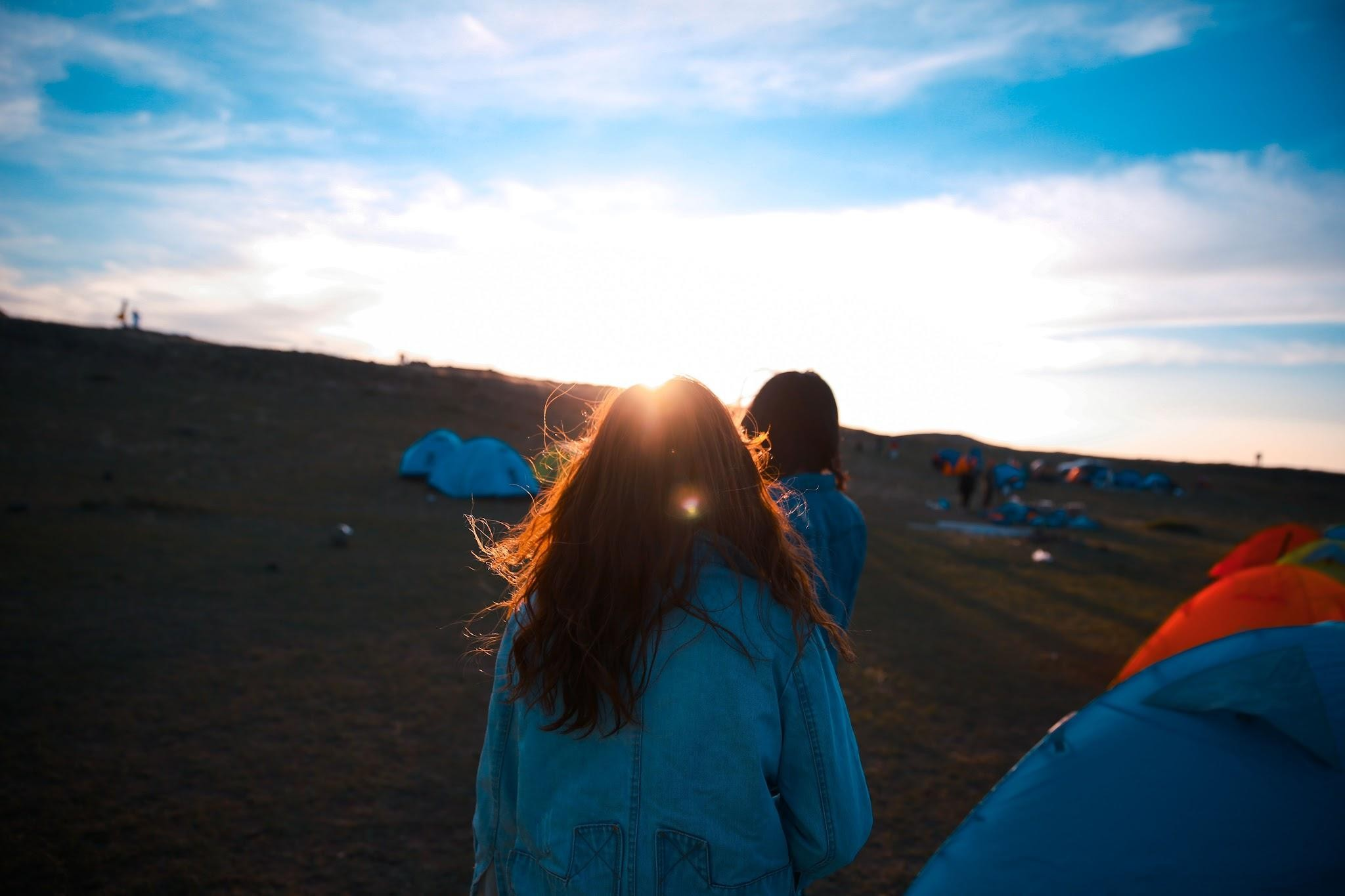 A camping scene at sunset with tents and people enjoying the outdoors A camping scene at sunset with tents and people enjoying the outdoors.